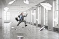 Jumping businessman in office . Mixed media Royalty Free Stock Photo
