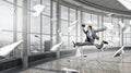 Jumping businessman in office . Mixed media Royalty Free Stock Photo