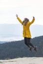 Jumping girl on the top of mountain. Happy young woman conquered the top. Concept of freedom. Vertical view Royalty Free Stock Photo