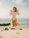 Jumping happy woman in swimsuit on ocean beach at sunset. Summer holidays Royalty Free Stock Photo