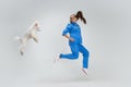 Portrait of young beautiful woman, female veterinary, vet doctor and sweet cute white poodle dog jumping  over Royalty Free Stock Photo