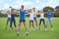 Jumping jacks, women and group outdoor for exercise on sports field and energy for cardio in fitness class. Health
