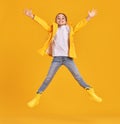 Jumping kid in raincoat and gumboots