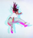 Jumping mixed race young girl jumping in colourful neon studio light. Female dancer performer moving in hip hop dance Royalty Free Stock Photo