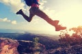 Jumping over precipice between two rocky mountains at sunset Royalty Free Stock Photo