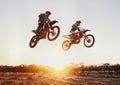 Jumping over the sunset. A shot of two motocross riders in midair during a race. Royalty Free Stock Photo