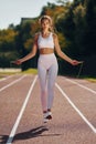 Jumping on the running track. Young woman in sportive clothes is exercising outdoors Royalty Free Stock Photo