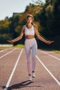 Jumping on the running track. Young woman in sportive clothes is exercising outdoors Royalty Free Stock Photo