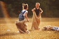 Jumping sack race outdoors in the field. Kids have fun at sunny daytime