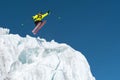 A jumping skier jumping from a glacier against a blue sky high in the mountains. Professional skiing