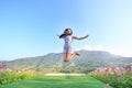 Jumping Young Asian woman feeling free with arms wide open at beautiful trees and mountains on blue sky Royalty Free Stock Photo