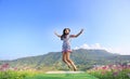 Jumping Young Asian woman feeling free with arms wide open at beautiful trees and mountains on blue sky Royalty Free Stock Photo