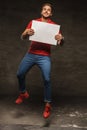 Jumping young man in jeans and red t shirt holding white sheet o Royalty Free Stock Photo