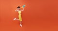 Jumping Young woman happy beauty with water gun and during Songkran festival studio shot on copy space orange background Royalty Free Stock Photo