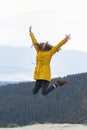 Jumping young woman on top of mountain. Happy tourist woman conquered the top. Concept of freedom Royalty Free Stock Photo