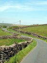 junction on a winding narrow country lane bordered by dry stone walls in hilly yorkshire dales countryside with blue summer sky Royalty Free Stock Photo