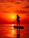 June 25, 2021. Anapa, Russia. Silhouette of woman paddle on stand up paddle board at quiet sea with sunset. Woman on Red Paddle