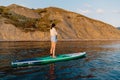 June 21, 2021. Anapa, Russia. Sporty woman paddle on stand up paddle board at sea in evening. Woman on Red Paddle sup board