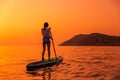 June 21, 2021. Anapa, Russia. Sporty woman paddle on stand up paddle board at sea with sunset or sunrise. Woman on Red Paddle sup