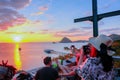 June 13, 2018 : An Asian female tourist with straw hat taking a picture of the boat aligned with the sunset on Labuan Bajo