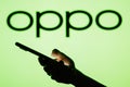 June 13, 2023, Brazil. OPPO logo seen in the background of a silhouette woman holding a mobile