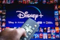 June 3, 2021, Brazil. In this photo illustration a person holds the TV remote control and in the background, the Disney+ Plus