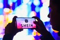 June 4, 2022, Brazil. In this photo illustration, a silhouetted woman holds a smartphone with the Shein logo displayed on the Royalty Free Stock Photo