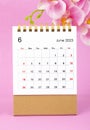 The June 2023 calendar desk and pink orchid on pink background