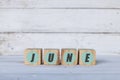june concept written on wooden cubes or blocks, on white wooden background.