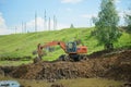 Construction equipment, a dump truck, an excavator and a tractor dig the ground for a reservoir. The village of