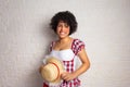 June Festival in Brazil. Young black woman with afro hairstyle in traditional plaid clothes holding straw hat