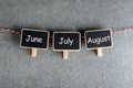 June, July and August - three summer month on little wooden tag. Summer calendar