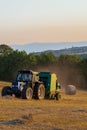 A hay baler at work in an Umbrian field as the sun sets. Royalty Free Stock Photo