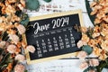 June 2024 monthly calendar with flower bouquet decoration on wooden background