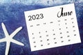 The June 2023 Monthly calendar with Starfish on blue wooden background