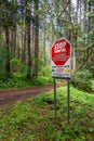 June 2022 - Nanaimo, Canada: No Dumping sign and hiking trail in green forest.