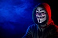 June 5, 2022 Novosibirsk, Russia: Hooded portrait of Anonymous in the dark in red-blue smoke.