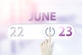 June 23rd. Day 23 of month, Calendar date.Hand finger switches pointing calendar date on sunlight office background. Summer month