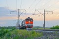 A Russian Railways locomotive carries a freight train on a summer evening