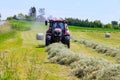 2 June 2021 Skutec, Czech Republic: After mowing, a red tractor collects hay in bales on a large field.