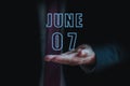 june 7th. Day 7 of month, announcement of date of business meeting or event. businessman holds the name of the month and day on