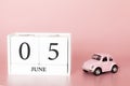 June 05th. Day 5 of month. Calendar cube on modern pink background with car