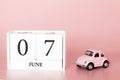 June 07th. Day 7 of month. Calendar cube on modern pink background with car