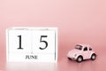 June 15th. Day 15 of month. Calendar cube on modern pink background with car