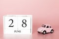 June 28th. Day 28 of month. Calendar cube on modern pink background with car