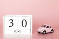 June 30th. Day 30 of month. Calendar cube on modern pink background with car