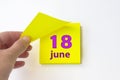 June 18th. Day 18 of month, Calendar date. Hand rips off the yellow sheet of the calendar. Summer month, day of the year concept