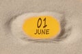 June 1 . 1th day of the month, calendar date. Hole in sand. Yellow background is visible through hole