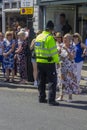 A uniformed police officer on street duty directing tourists close to Windsor Castle which is a famous Royal Residence in Windsor