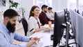 Junior female professional working in modern IT office. Group of young and experienced programmers and software